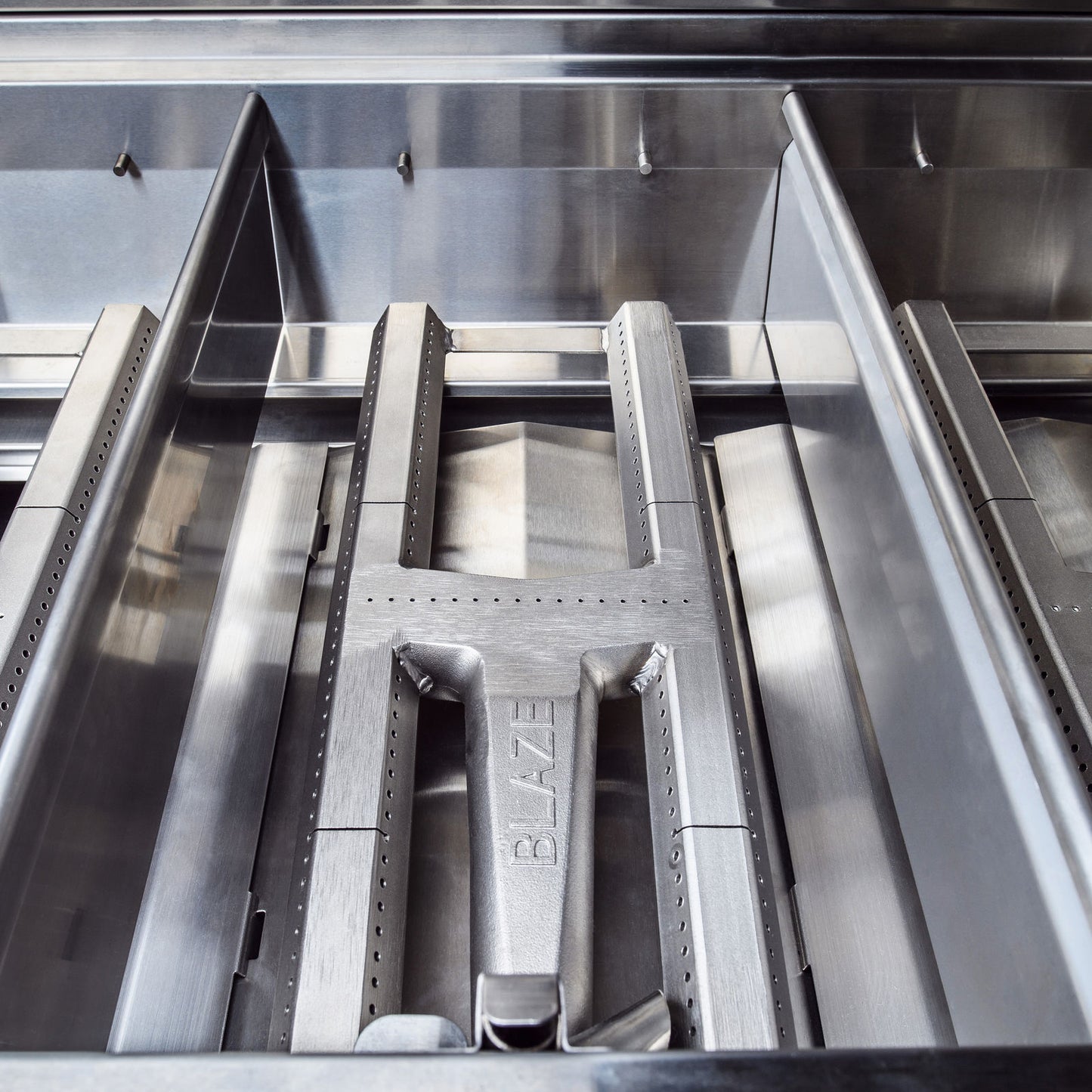 Commercial-grade cast stainless steel H-burners inside the Blaze Professional 34-inch natural gas grill, ensuring powerful and even heat distribution